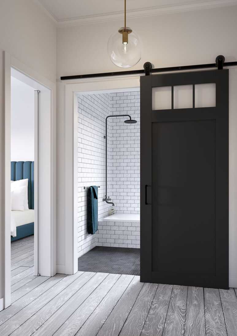 A black barn door enhances the minimalist design for a black and white bathroom