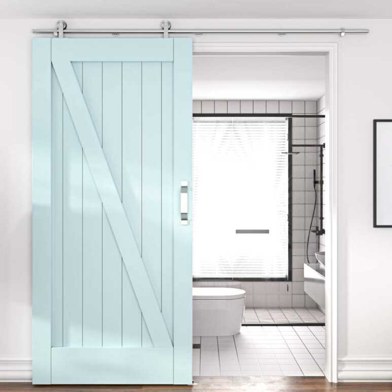 A blue mint barn door brightens up the black and white bathroom