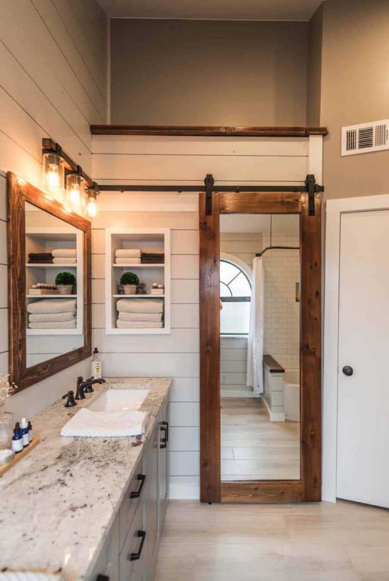 A mirrored cedar barn door in a modern farmhouse-style bathroom