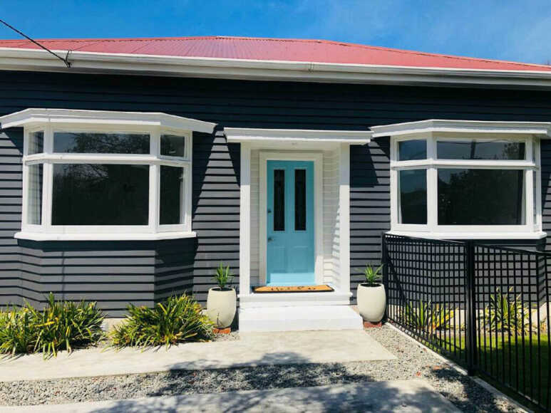 A pop vibe in a mid-century style by putting a blue door in a grey house and white trim