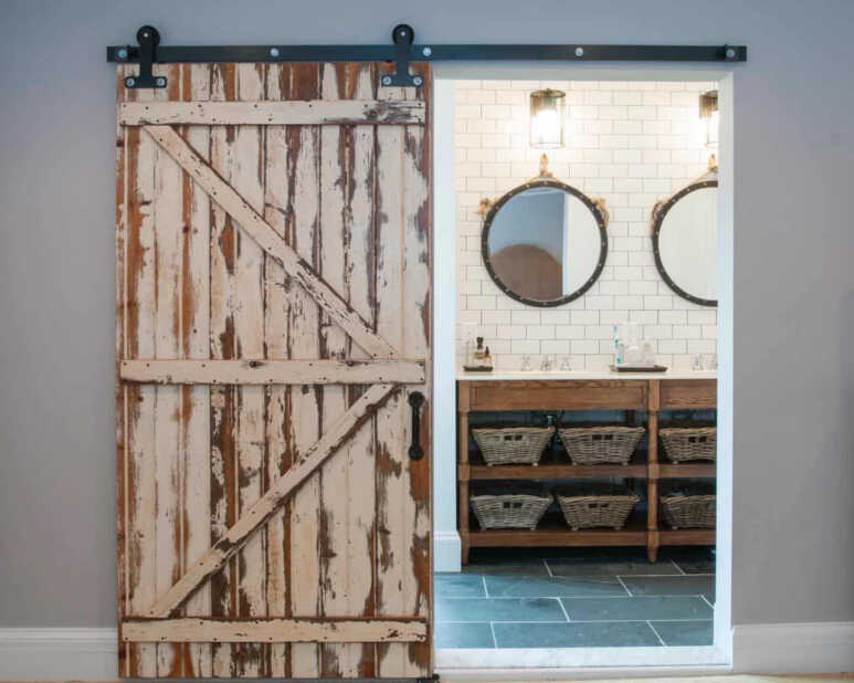 A rustic white barn door accentuates the rustic bathroom decoration