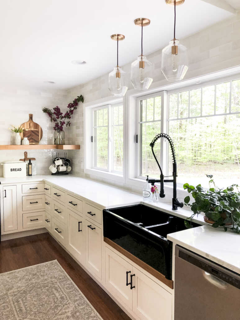 A striking black sink in a white farmhouse-style kitchen