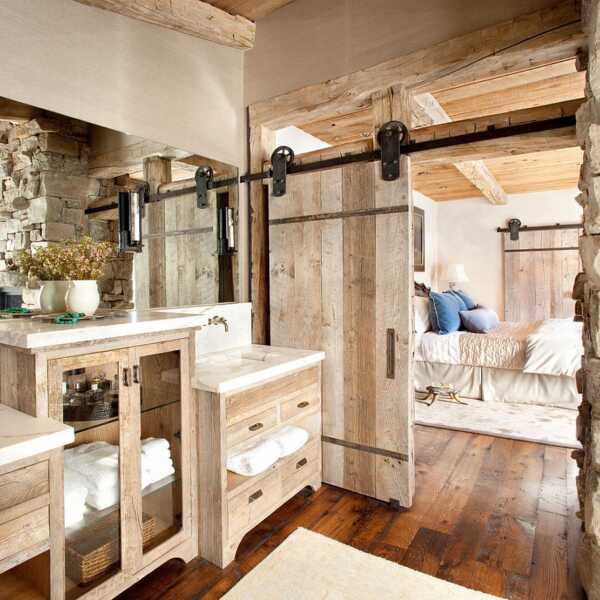 A wood barn door nicely matched with wooden furniture in a rustic stone house