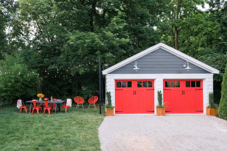 Carriage-style garage doors colored in coral red look lively in a stand-alone garage