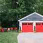 Carriage-style garage doors colored in coral red look lively in a stand-alone garage