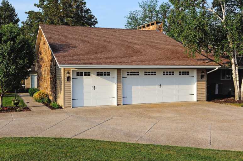 Classic white carriage-style garage doors in a farmhouse enhance the appealing charm
