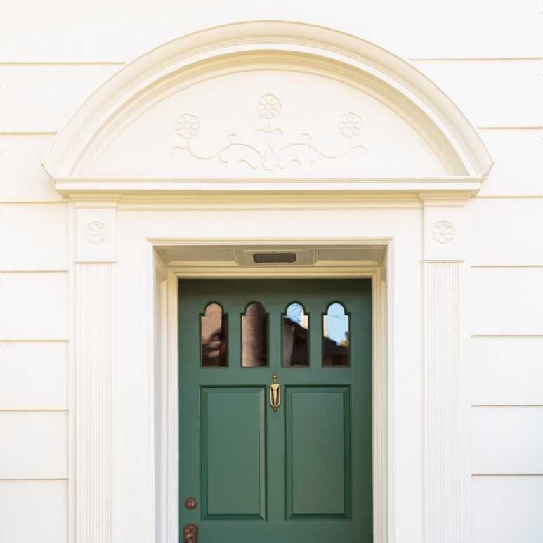 Modern Como green craftsman-style front door enhances the beauty of the half-round pediment in a tan house