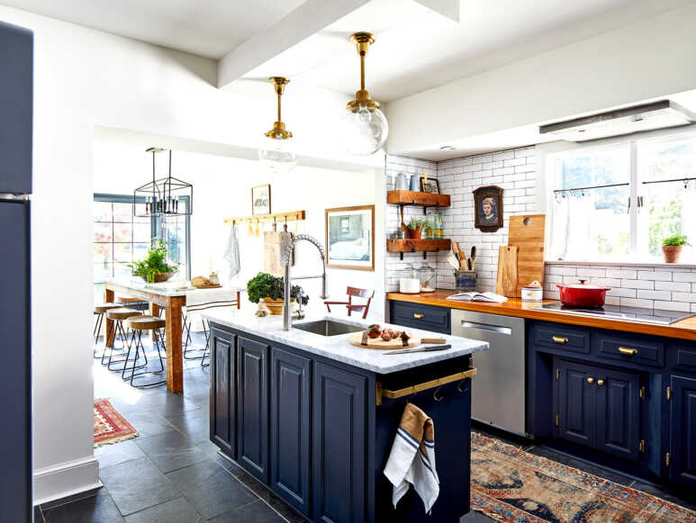 Navy blue kitchen cabinets matched perfectly with wood and golden elements to create layers of texture to a rustic and contemporary kitchen