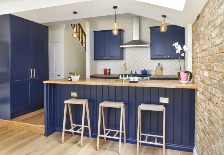 Navy blue kitchen cabinets matched with layers of wooden elements and golden details for a classic and warm wooden kitchen