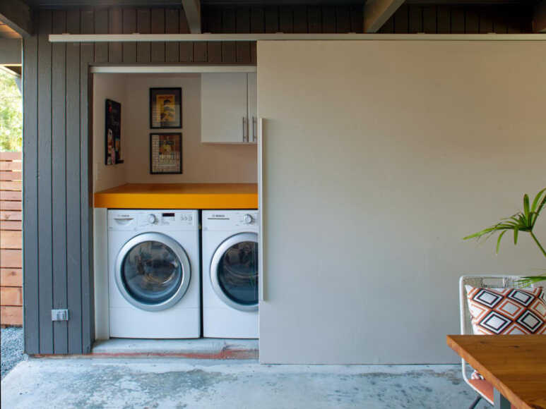 The Sliding door for the outdoor laundry room looks superb with a wooden wall and concrete flooring
