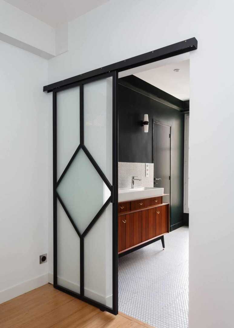 Using a sliding bathroom door in black and white colors to create a small partition between the rooms