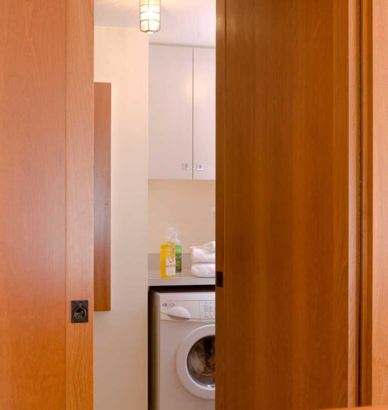 Wooden flat-panel door for an all-white laundry room to add warmth and extra comfort